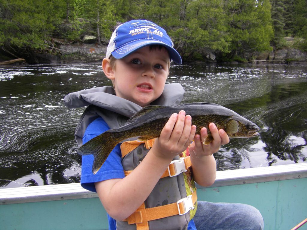 A little boy shows off the trout he caught at Goat camp.