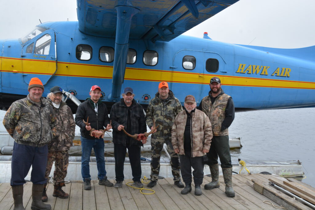 Men standing by the float plane getting ready for the moose hunt.